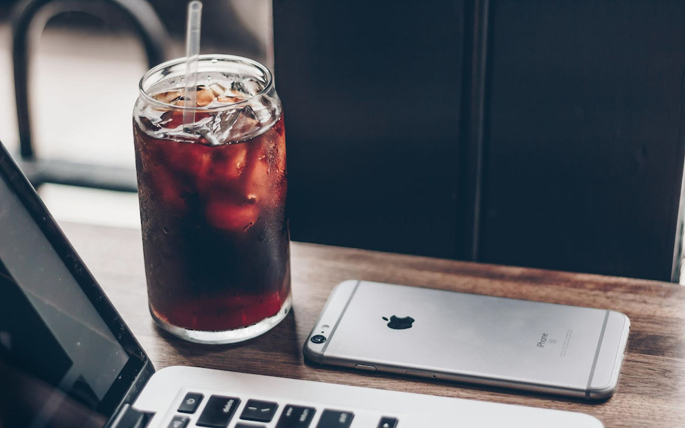 Cold brew in a glass next to iphone and macbook
