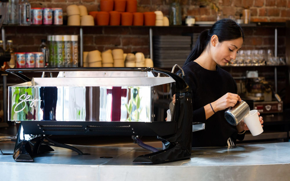 barista working behind the counter with slayer espresso machine in foreground