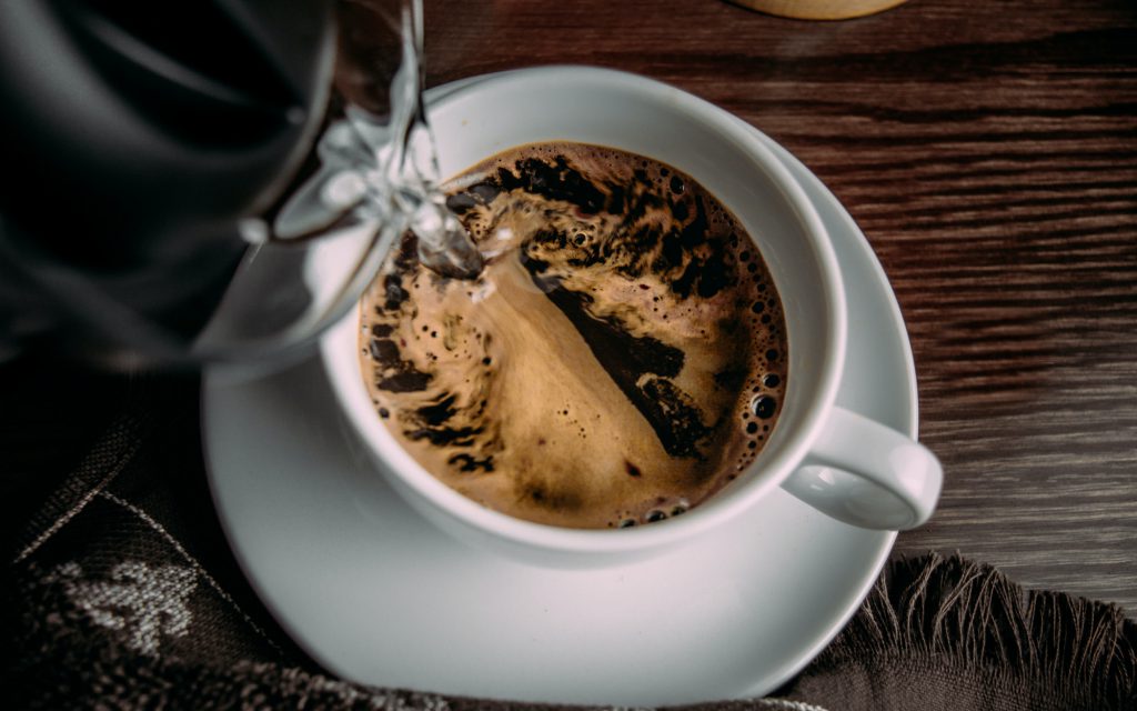 A person pours hot water into a cup of instant coffee.