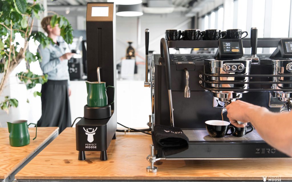 A barista uses a Perfect Moose automated milk foamer and a Dalla Corte Zero espresso machine.