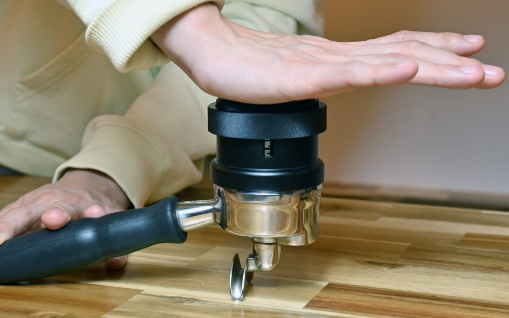 A barista demonstrates correct tamping technique for espresso.