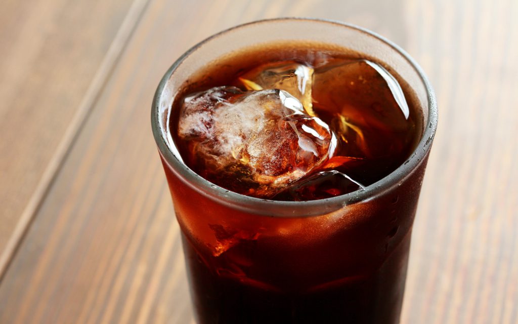 A glass of cold brew coffee on a wooden table.