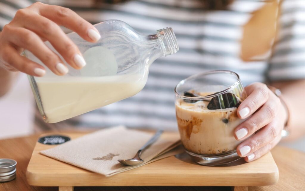 A woman practices cold brew safety as she pours milk.