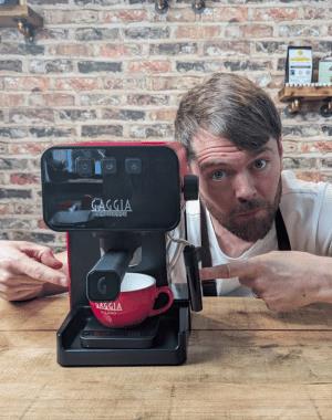 Espresso machine with the drip tray removed and a cup on a set of scales.