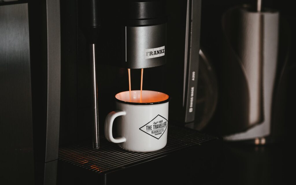 Coffee being extracted from a Franke coffee machine into a tin mug.