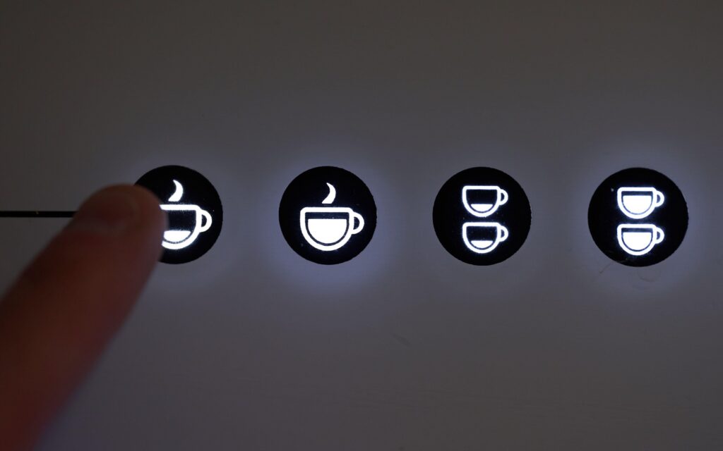 A person pushing a button on coffee machine.