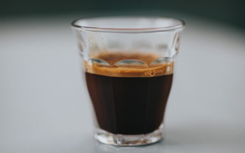 A single shot of espresso in a glass cup.