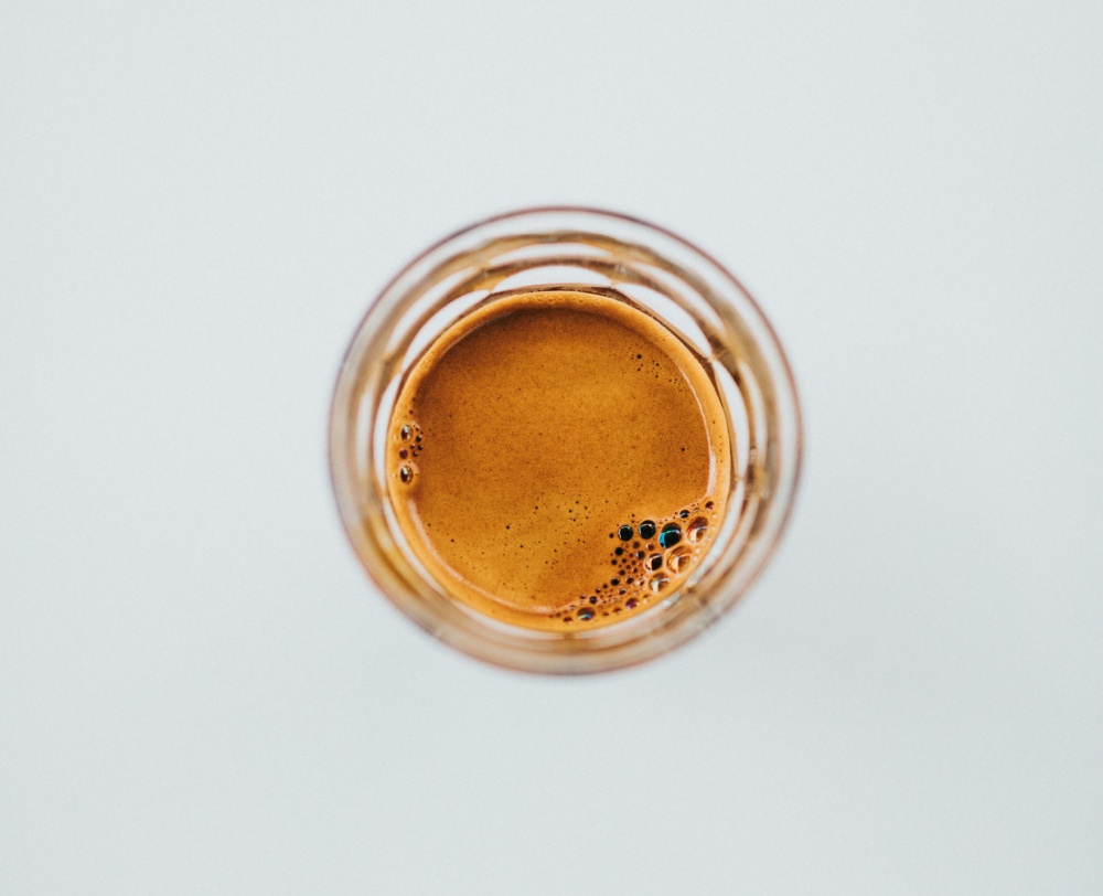 A shot of espresso in a glass with a thick layer of crema.