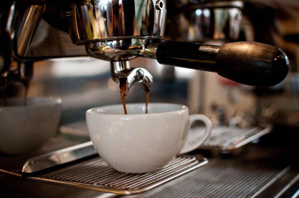 Extracting a double shot of espresso into a white ceramic mug.