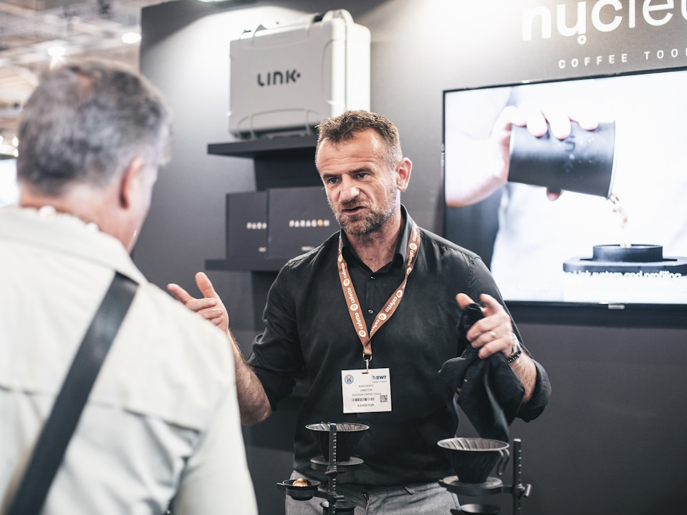 Coffee professional Sasa Sestic speaks to a person at a trade show.