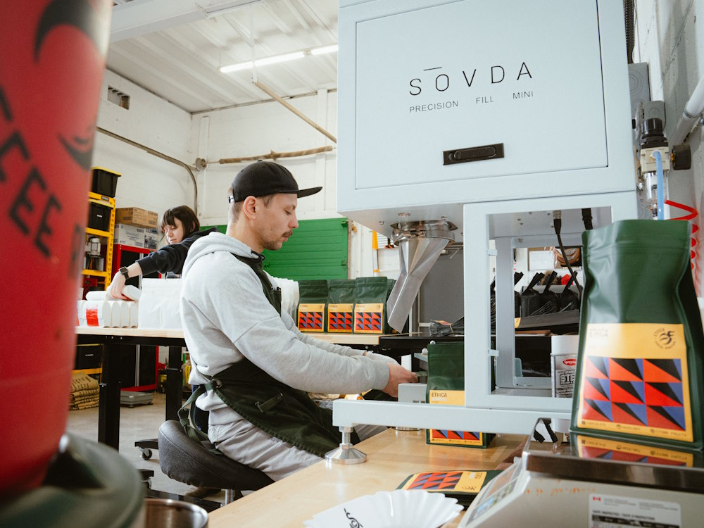 A roaster at Ethica Coffee packages coffee using a Sovda machine.